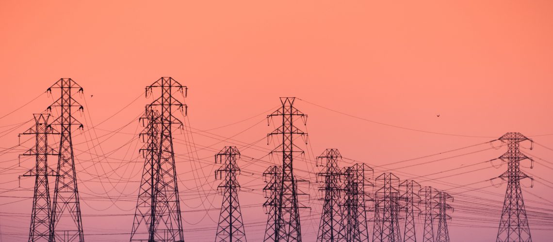 Sunset view of PG&E high voltage electricity towers on the shoreline of San Francisco bay area; California